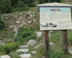 A Forest Service sign sits next to the old tank base stones today.