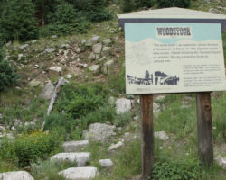 A Forest Service sign sits next to the old tank base stones today.