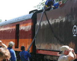 The crew tops off the water tank in 7081's tender with a hose from the fire plug.
