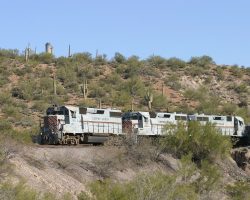 502 leads the local job through a cut directly above the main highway, with the smelter's main stack in the background
