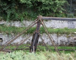 This is the giant T-rocker arm. Power arrives from the right, as that horizontal beam connects out to the wheel. On the left, not visible because of the foliage, is where the shaft coming up from the mines connects.