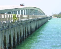 Continuing north, we see the Niles Channel bridge, again with highway decking still in place, and a missing segment near the middle to facilitate boat movements. The modern Overseas Highway bridge can be seen to the left (north) side of the old bridge.