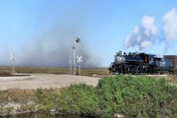 A field burns in the background to prepare it for harvesting as 148 waits at the USSC interlocking.